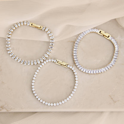 Minimal CZ tennis bracelet in gold over surgical steel, featuring a refined, understated design styled on a neutral marble surface.