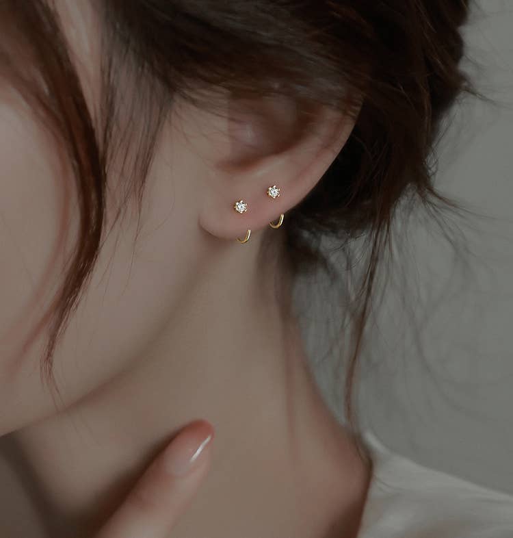 Minimal star stud earrings with small gold hoops, styled on an ear with a soft, understated jewelry aesthetic.