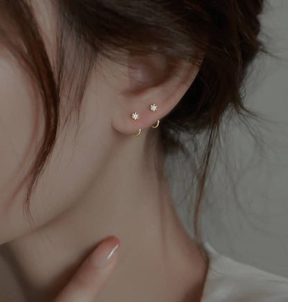 Minimal star stud earrings with small gold hoops, styled on an ear with a soft, understated jewelry aesthetic.