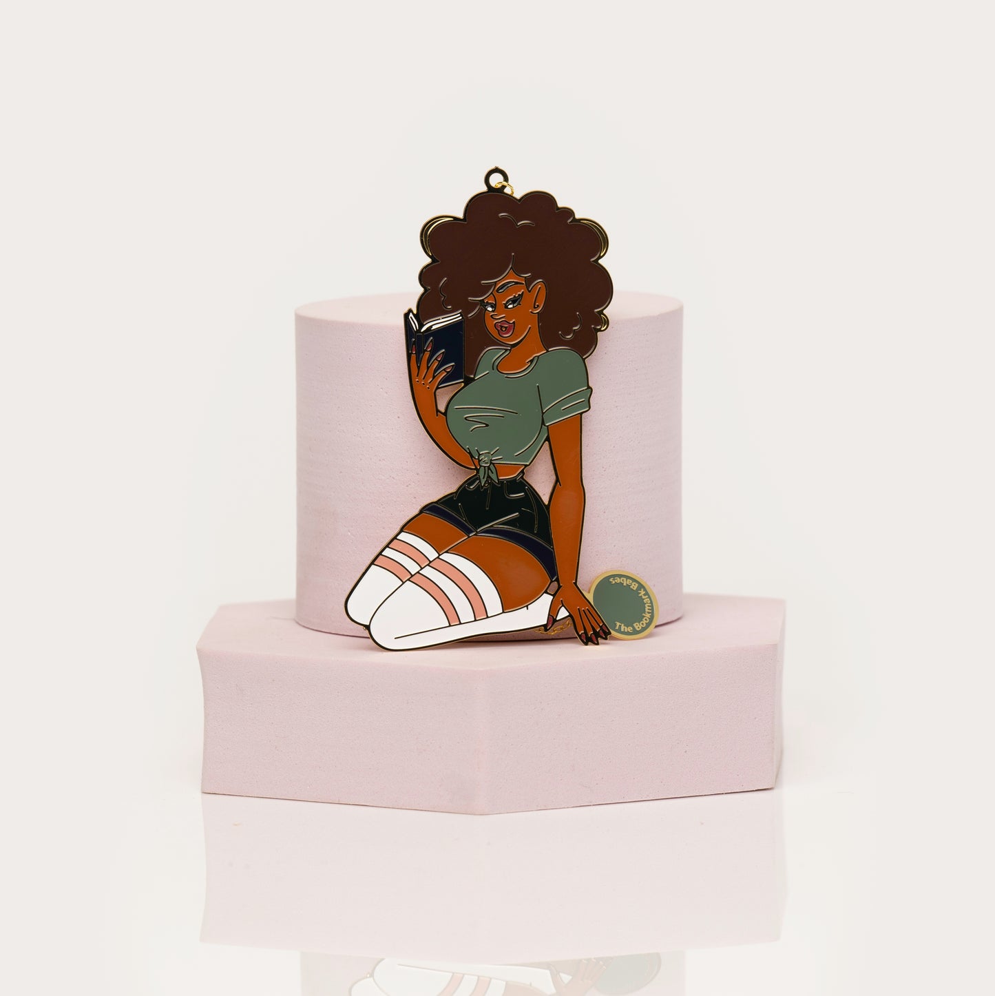 Enamel bookmark of Black woman with curly hair reading a book
