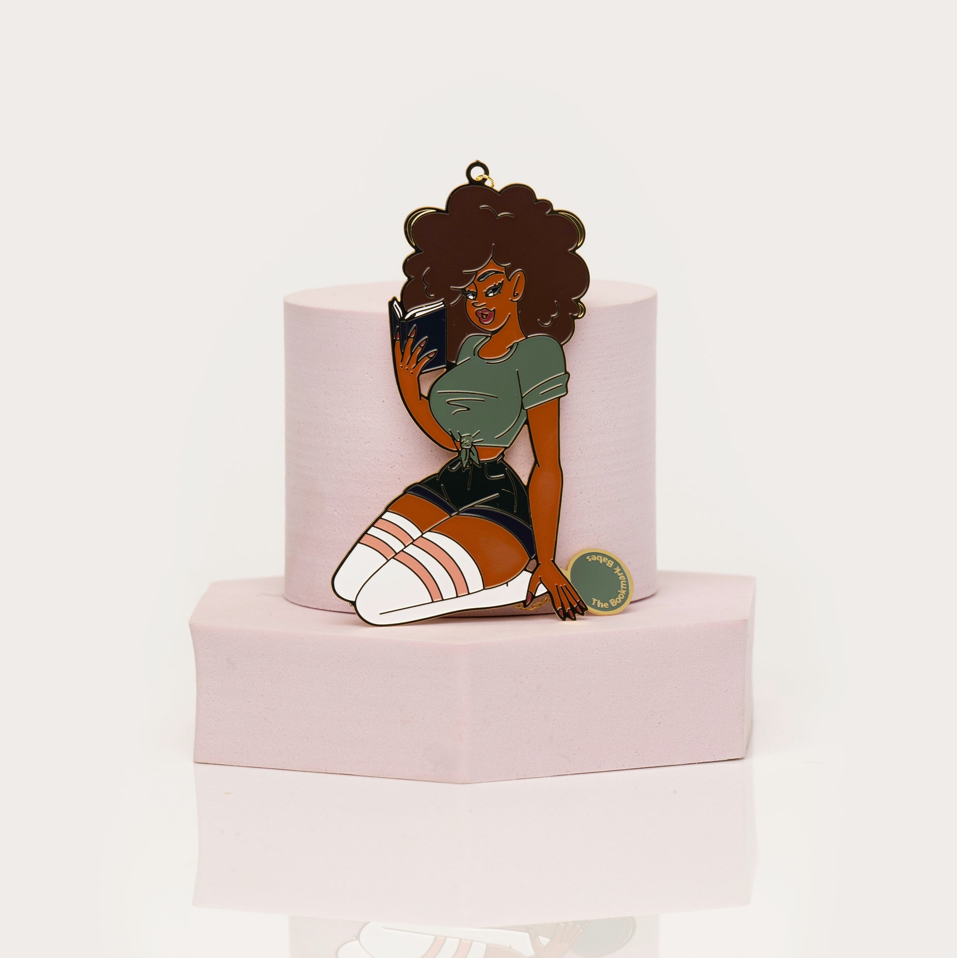 Enamel bookmark of Black woman with curly hair reading a book
