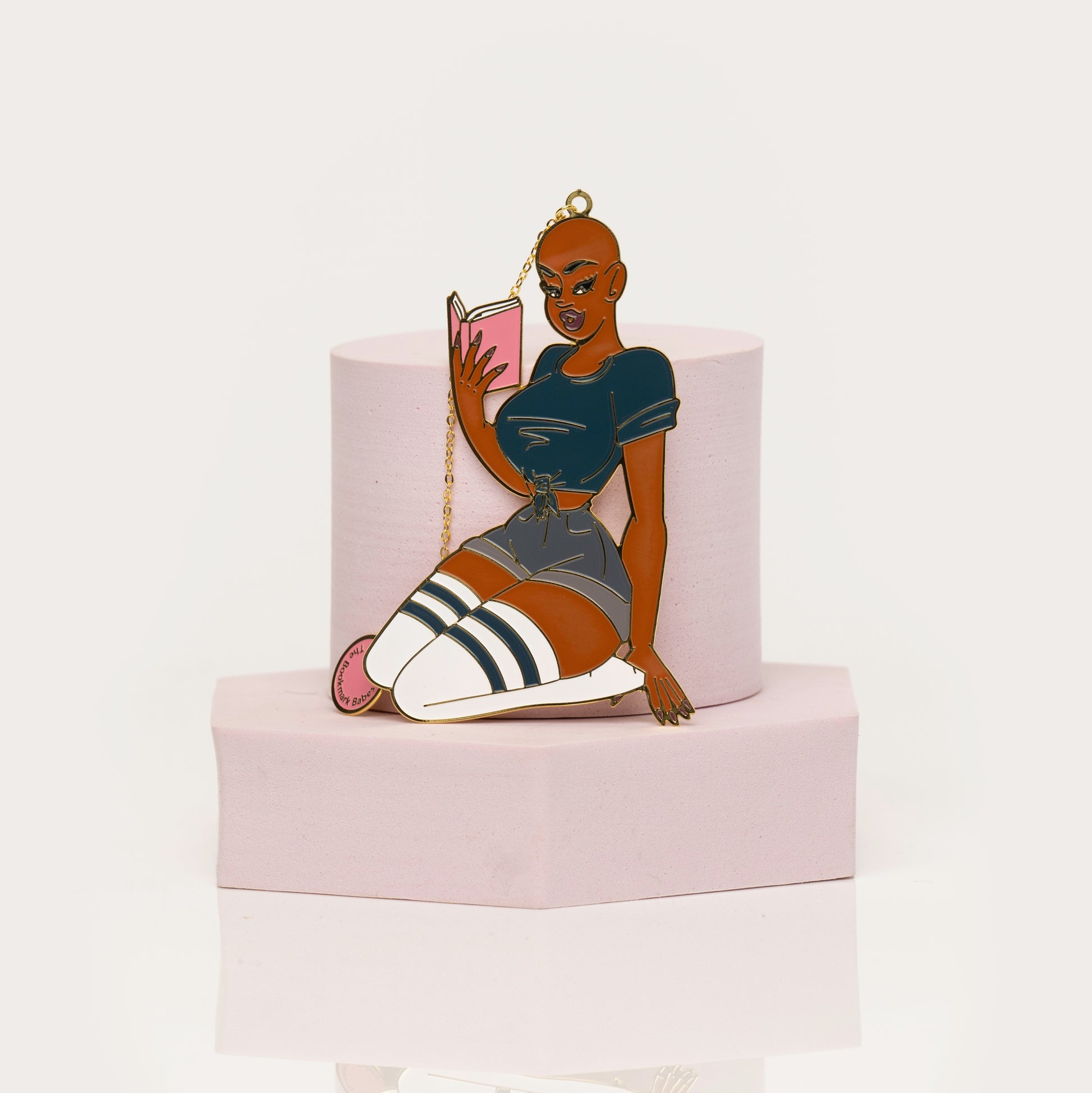 Feminine enamel bookmark featuring bold bald character with book
