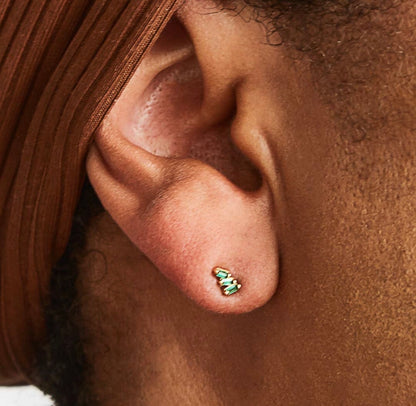 Green triple baguette CZ stud earrings in gold, worn on ear with a minimal, everyday jewelry aesthetic.