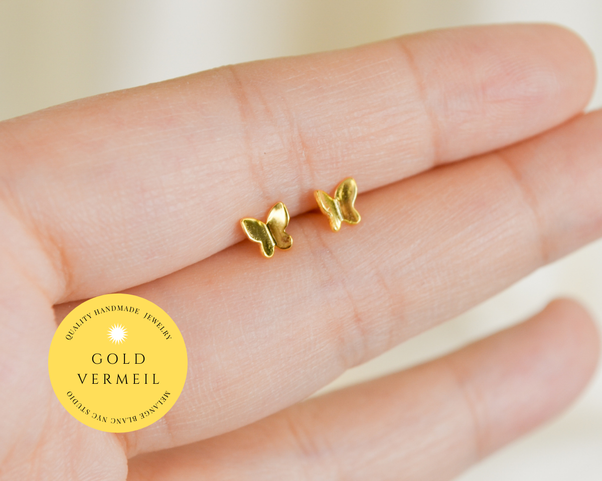 Minimal butterfly stud earrings in gold vermeil, styled on a neutral background with a refined, delicate aesthetic.